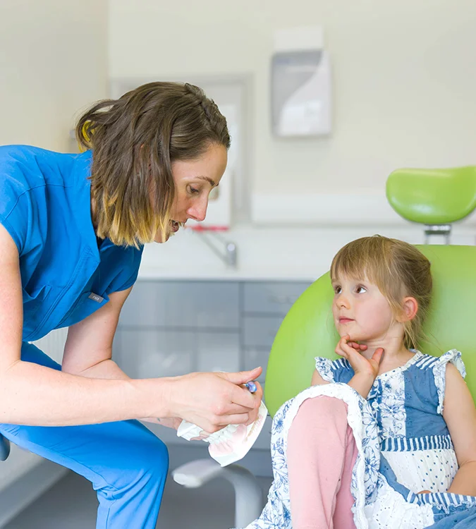 Dentist talking with a young girl sitting in the dental chair
