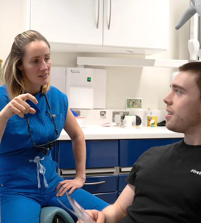 Dentist discussing treatment with a seated patient in the surgery