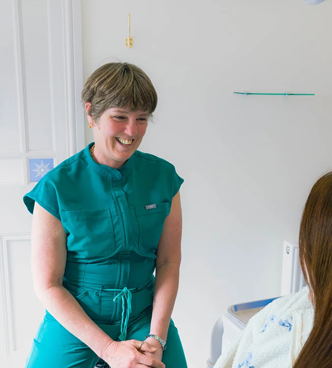 Smiling clinician in green scrubs talking with a patient