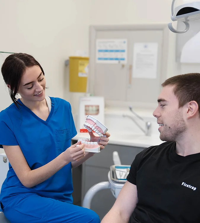 Hygienist showing a patient how to clean with a model of teeth