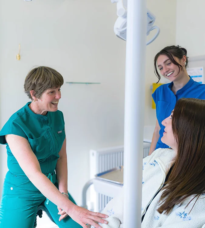 Dentist and nurse chatting with a patient in the treatment room