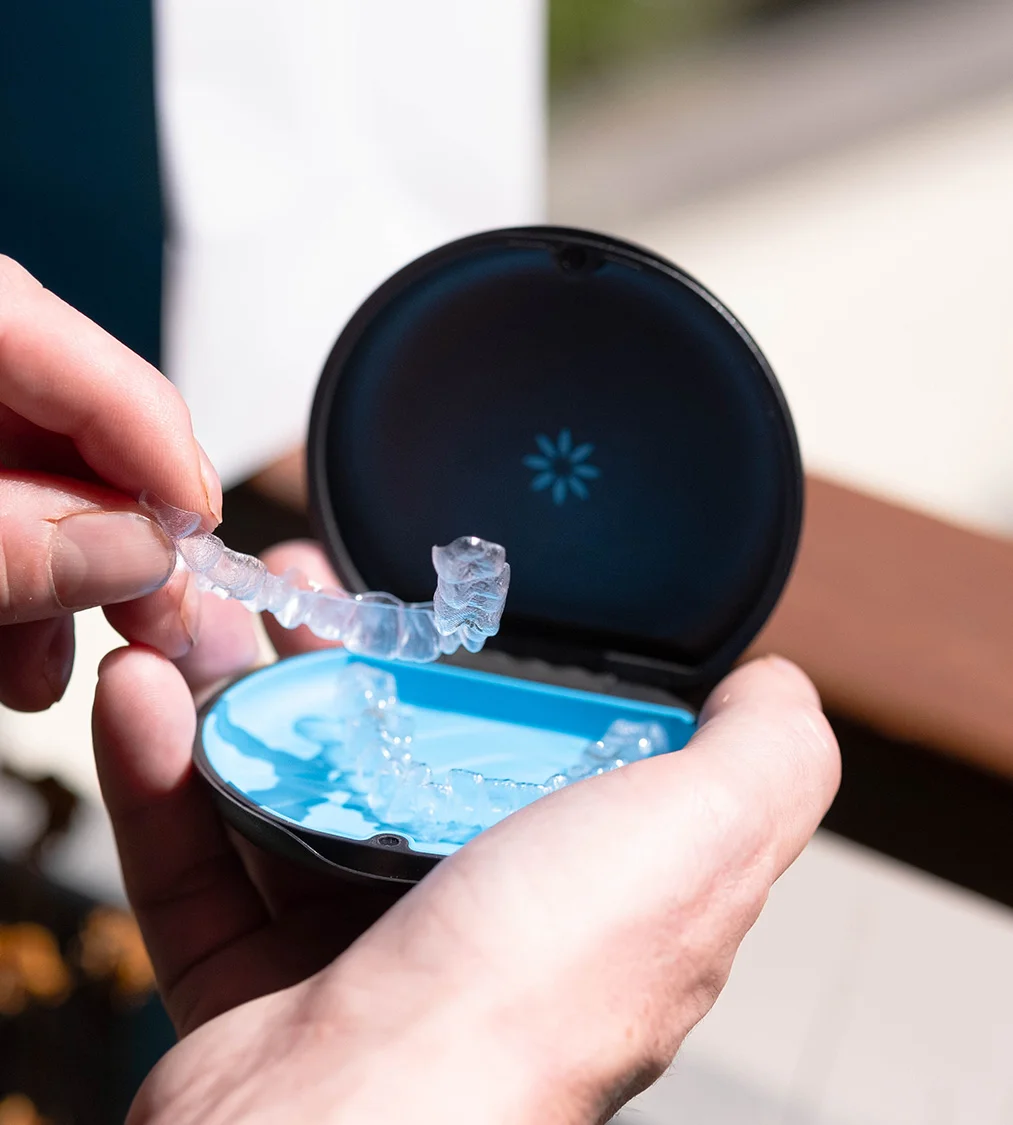 Patient taking a clear aligner out of its Invisalign case