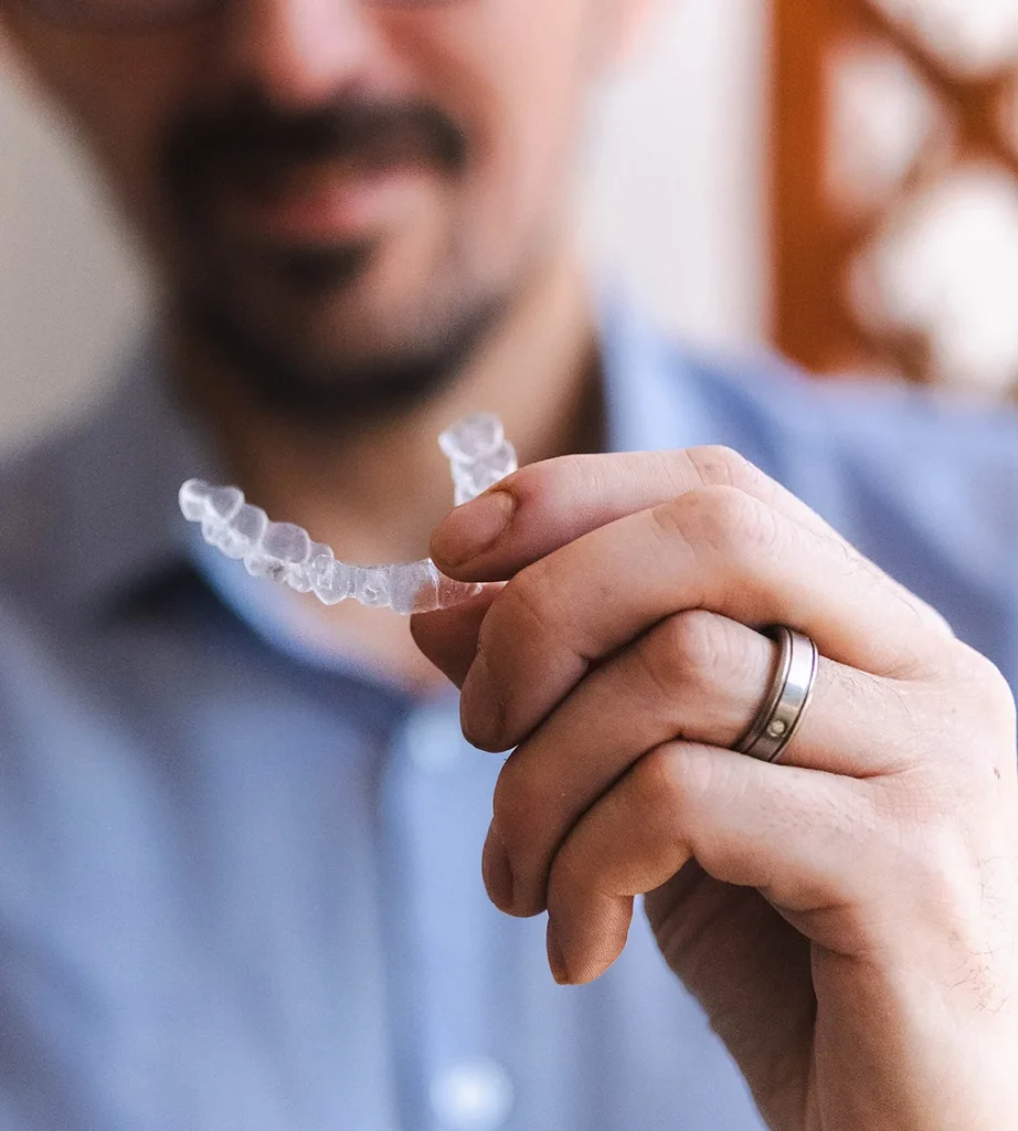 Smiling man holding a clear aligner