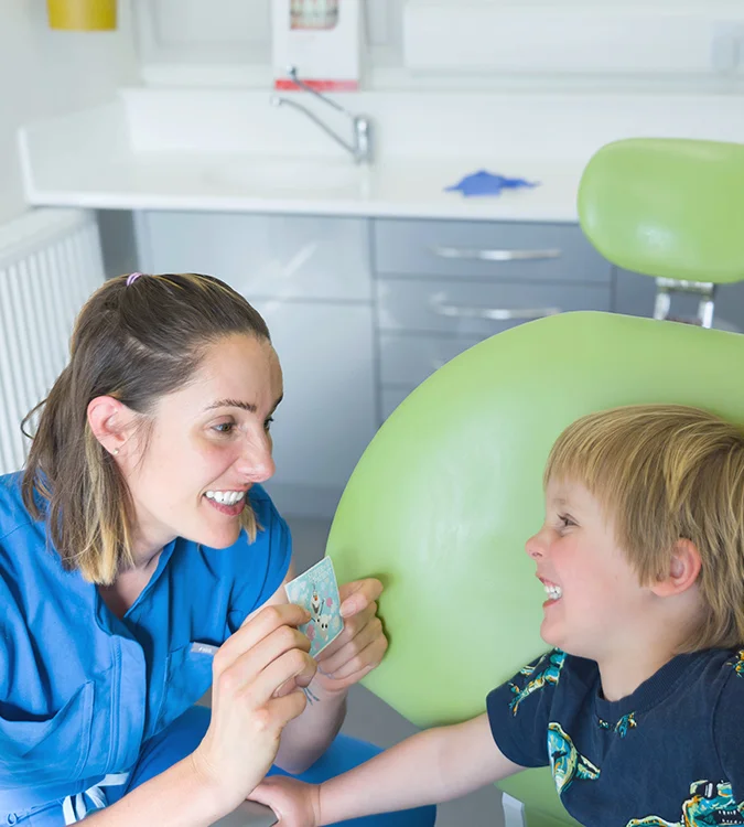 Dentist showing a toothbrush to a smiling young boy